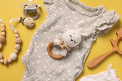 Different baby accessories on yellow background, flat lay