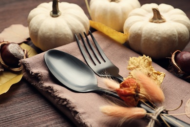 Photo of Autumn table setting, closeup, Cutlery with pumpkins and fallen leaves on wooden table