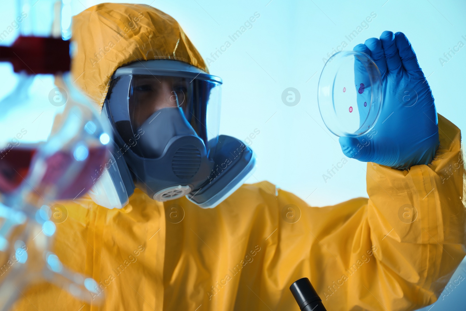 Photo of Scientist in chemical protective suit with Petri dish at laboratory. Virus research