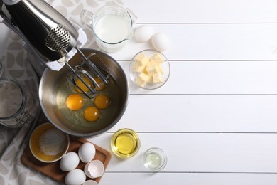 Photo of Making dough. Raw eggs in bowl of stand mixer and ingredients on white wooden table, flat lay with space for text