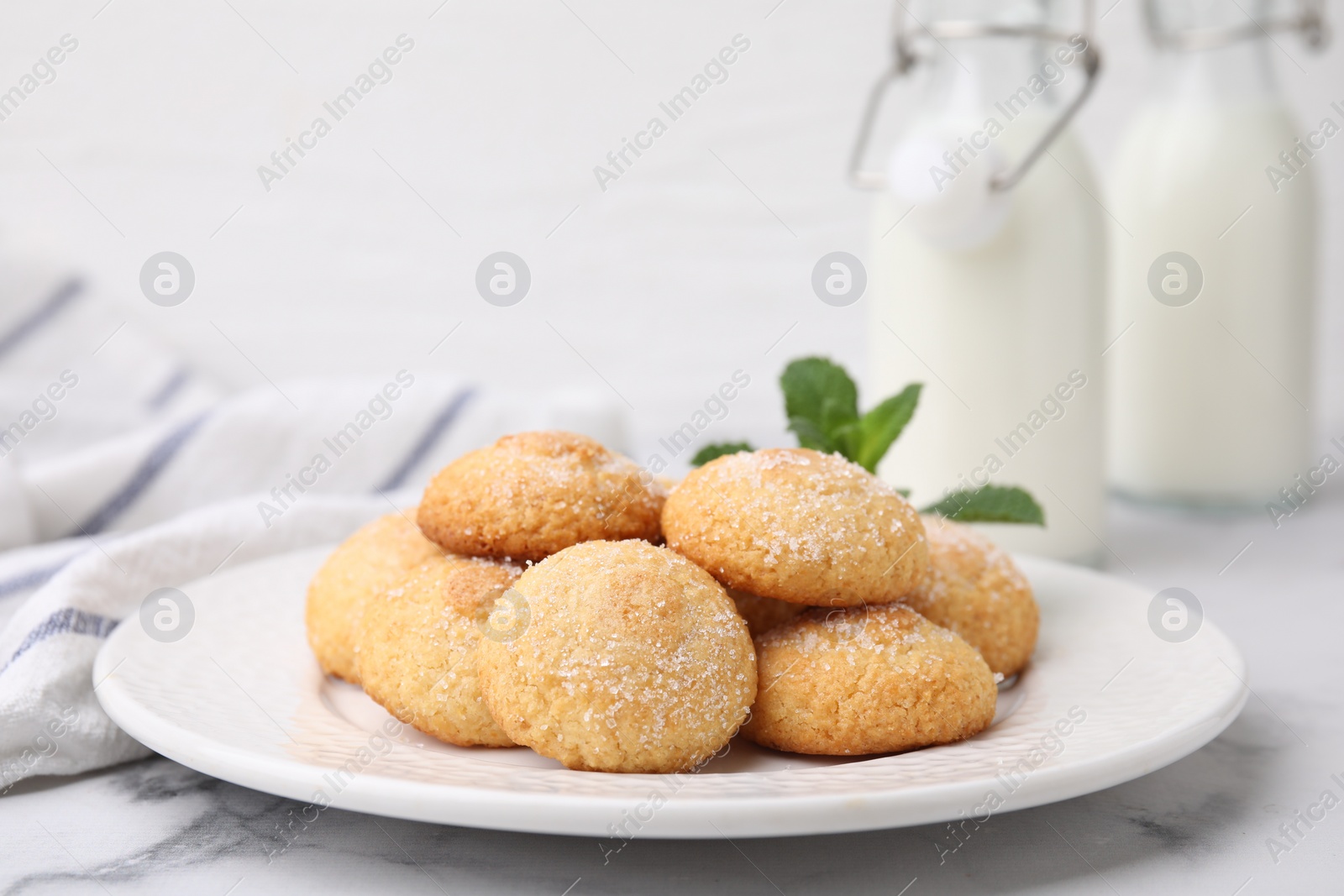 Photo of Tasty sweet sugar cookies and mint on white marble table, closeup