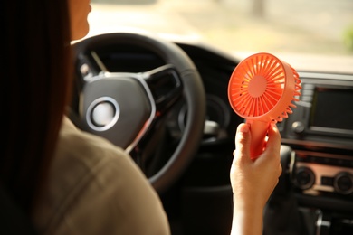 Photo of Woman with portable fan in car on hot summer day, closeup