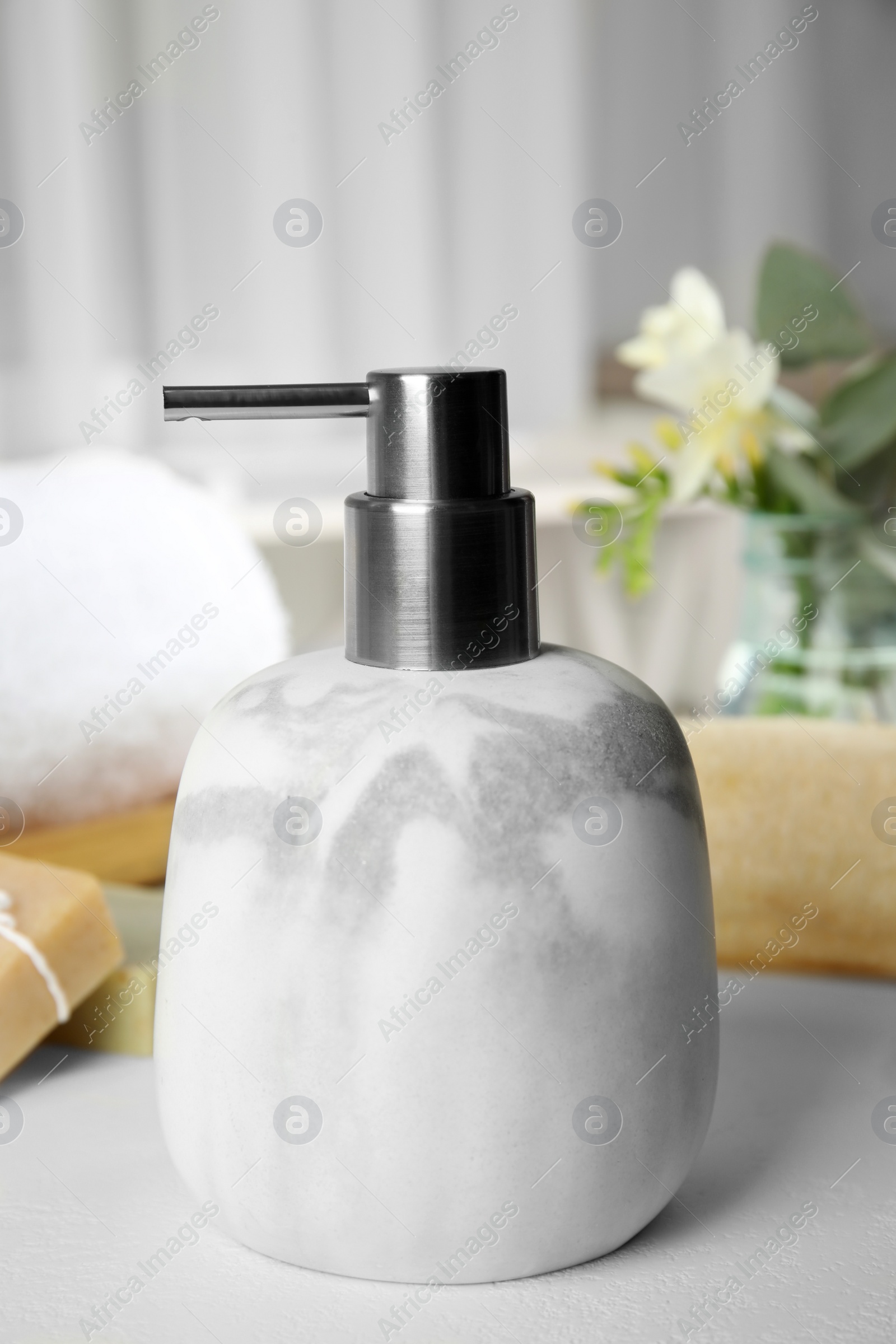 Photo of Modern marble soap dispenser on light table