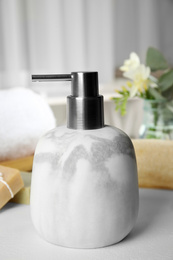 Photo of Modern marble soap dispenser on light table