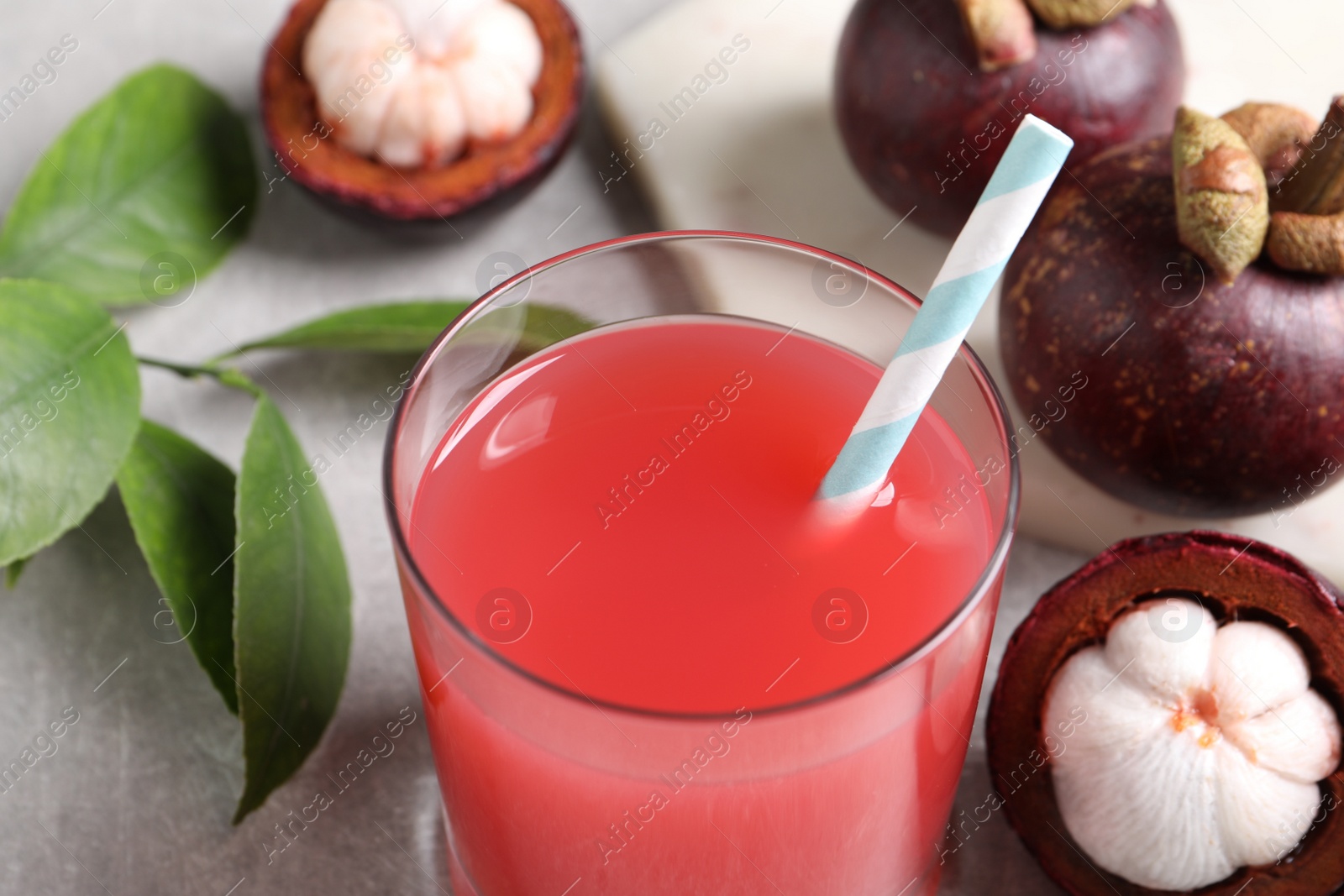 Photo of Delicious mangosteen juice in glass on light table, closeup