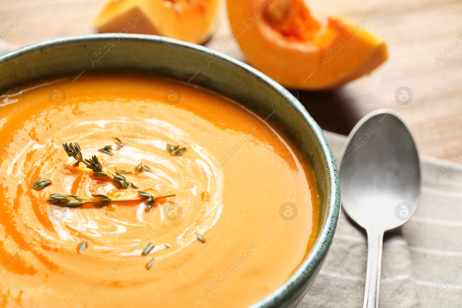 Photo of Delicious pumpkin cream soup with thyme in bowl on table, closeup