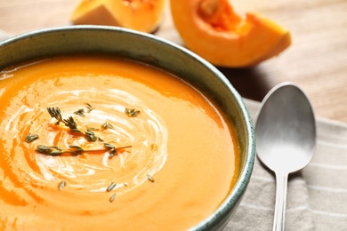 Delicious pumpkin cream soup with thyme in bowl on table, closeup