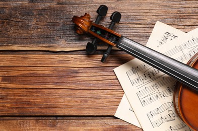 Photo of Violin and music sheets on wooden table, top view. Space for text