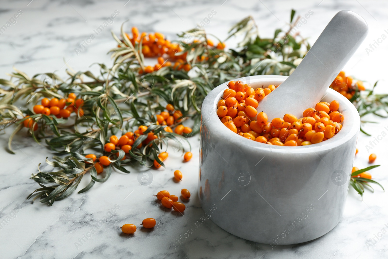 Photo of Ripe sea buckthorn berries on white marble table, closeup