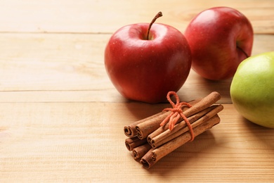 Fresh apples and cinnamon sticks on wooden table