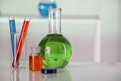 Photo of Laboratory analysis. Different glassware with liquids on white table against blurred background. Space for text