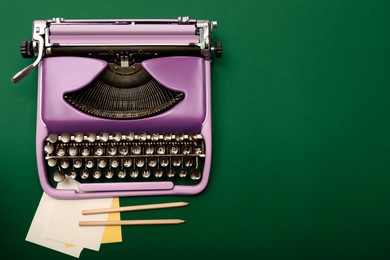 Copywriter. Vintage typewriter, paper notes and pencils on dark green background, top view. Space for text