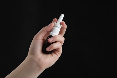 Woman with nasal spray on black background, closeup. Space for text