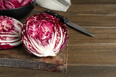 Photo of Halves of fresh ripe radicchio on wooden table, space for text
