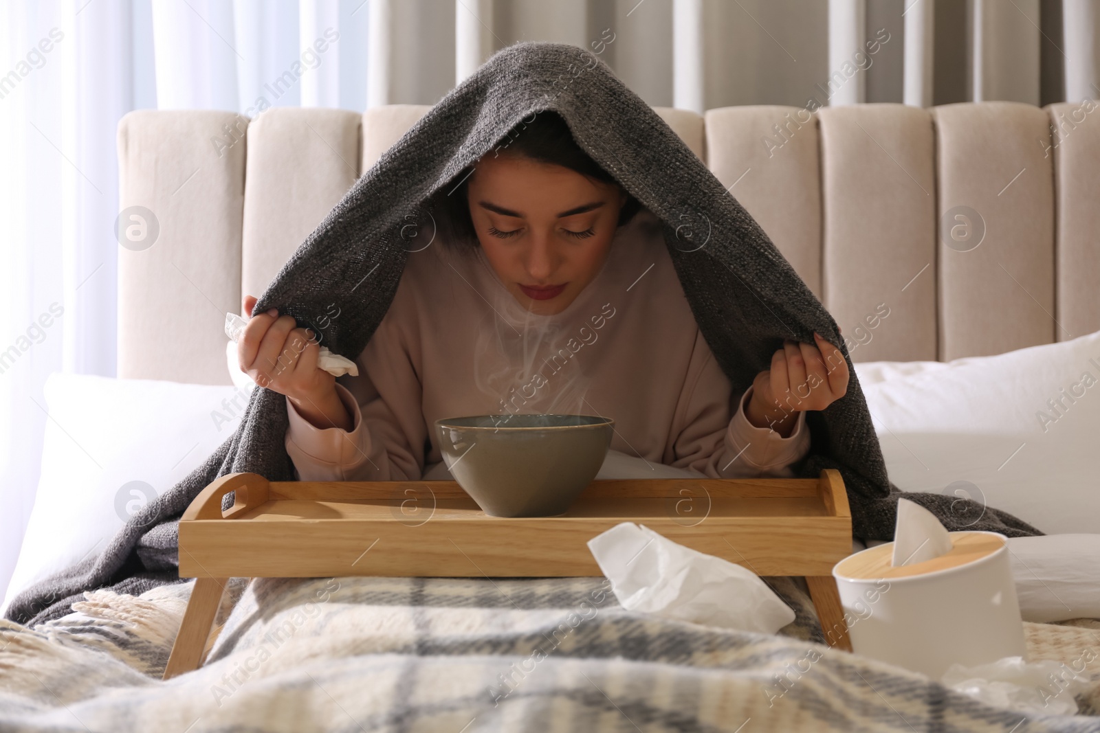 Photo of Woman with plaid doing inhalation above bowl on bed