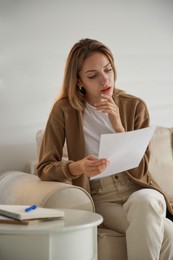 Photo of Woman reading letter on sofa at home