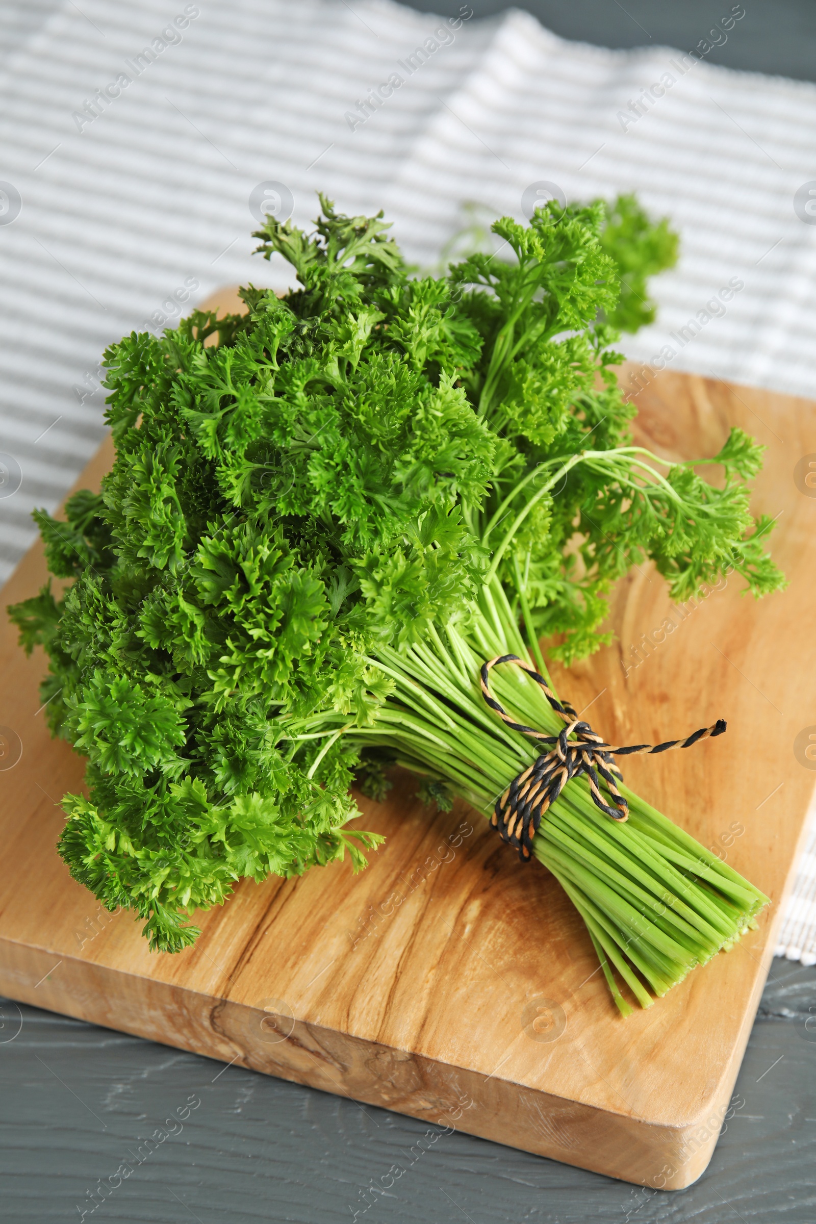 Photo of Wooden board with fresh green parsley on table