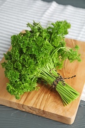 Wooden board with fresh green parsley on table