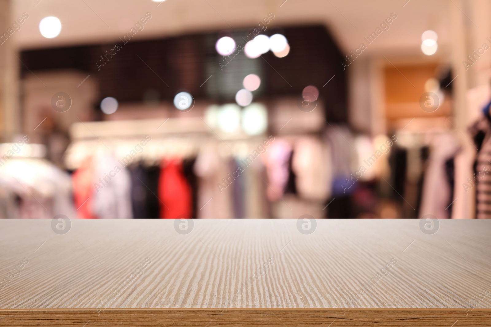 Image of Empty wooden table and blurred view of store with modern clothes