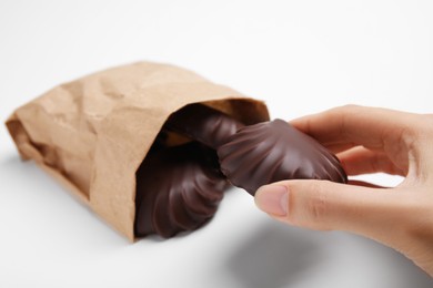 Photo of Woman holding delicious chocolate covered zephyr on white background, closeup