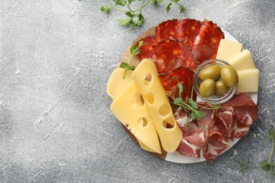 Serving board with delicious cured ham, cheese and olives on light grey table, flat lay. Space for text