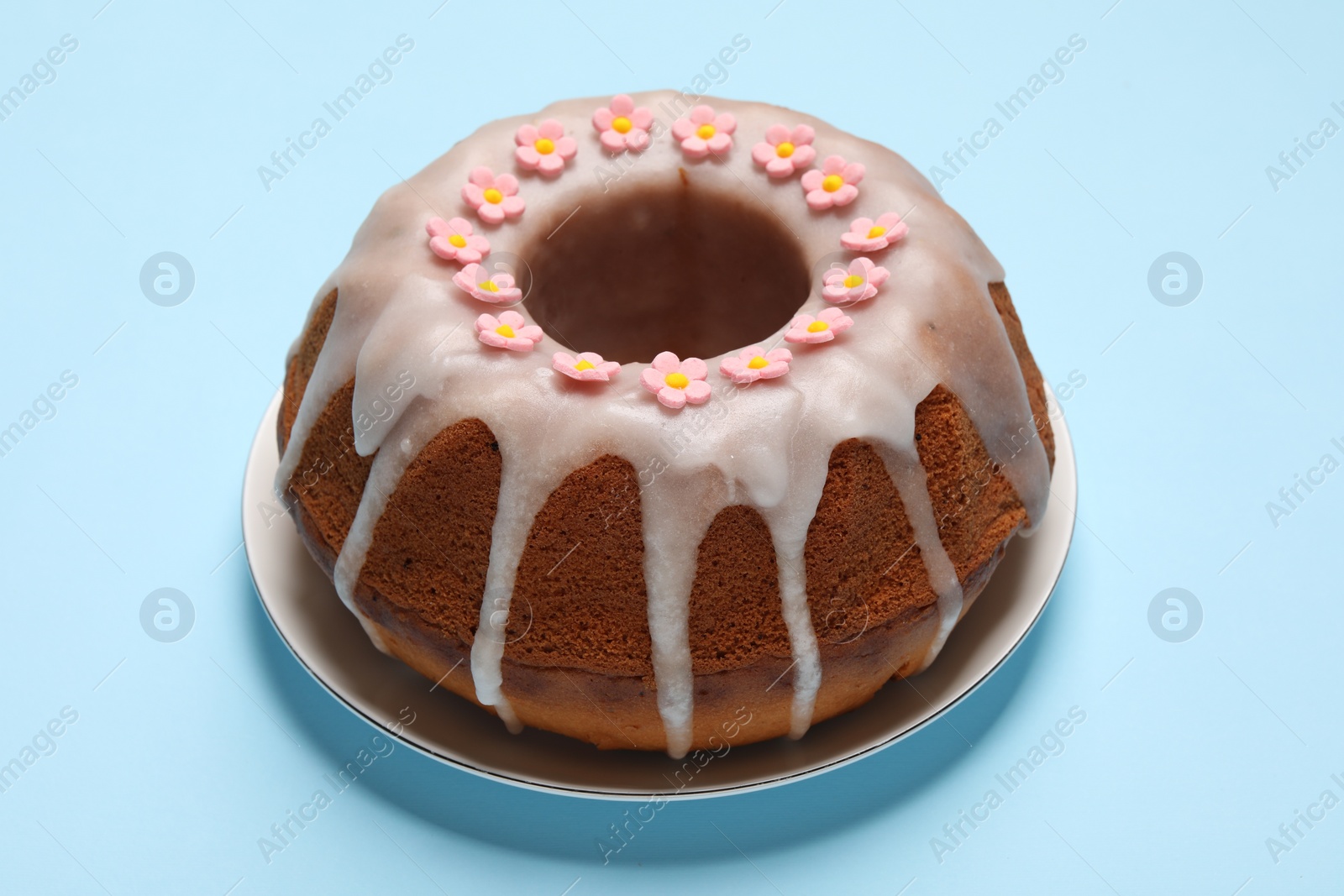 Photo of Delicious Easter cake decorated with sprinkles on light blue background, closeup
