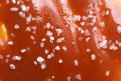Photo of Delicious caramel sauce with sea salt as background, top view