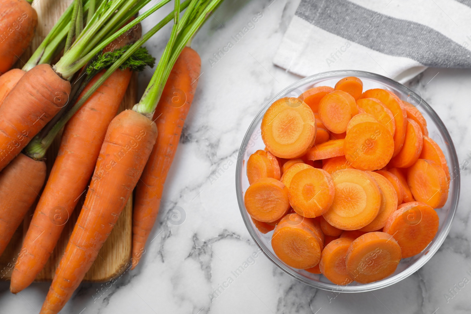 Photo of Whole and cut ripe carrots on white marble table, flat lay