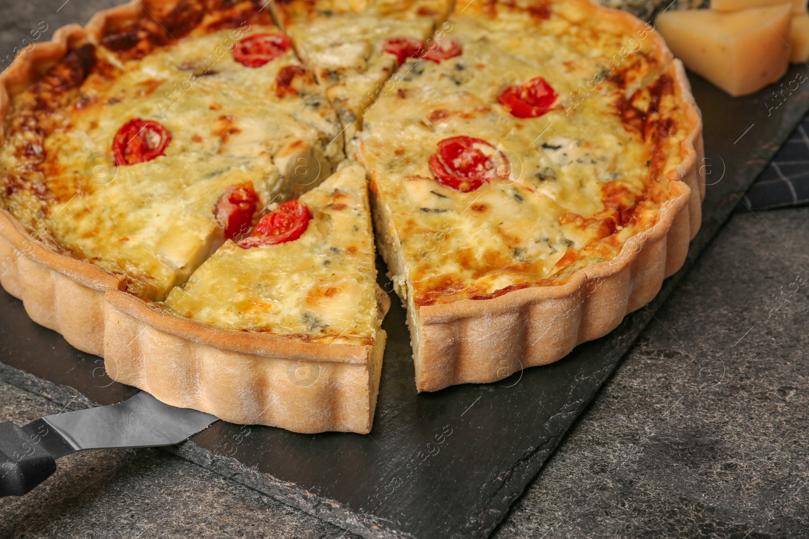 Photo of Taking piece of delicious homemade cheese quiche on gray table, closeup