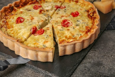 Photo of Taking piece of delicious homemade cheese quiche on gray table, closeup