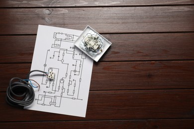 Wiring diagram, wires and disassembled light switch on wooden table, flat lay. Space for text