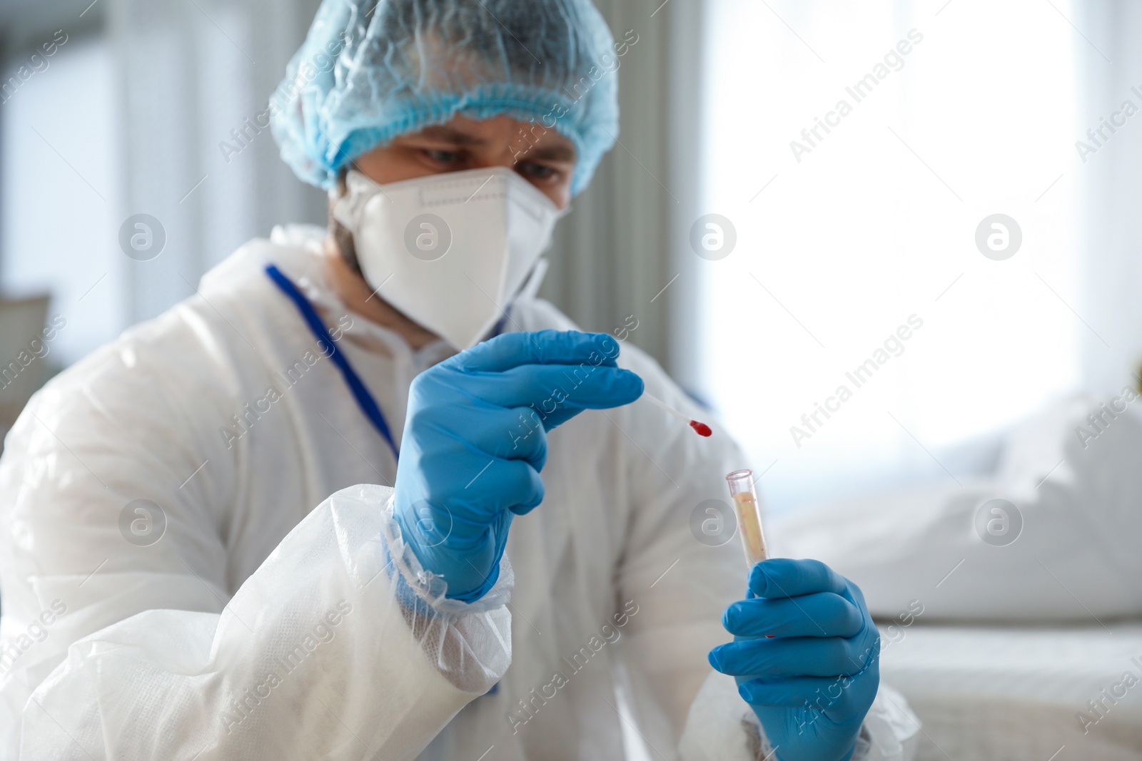 Photo of Investigator in protective suit working with blood sample at crime scene, focus on hands