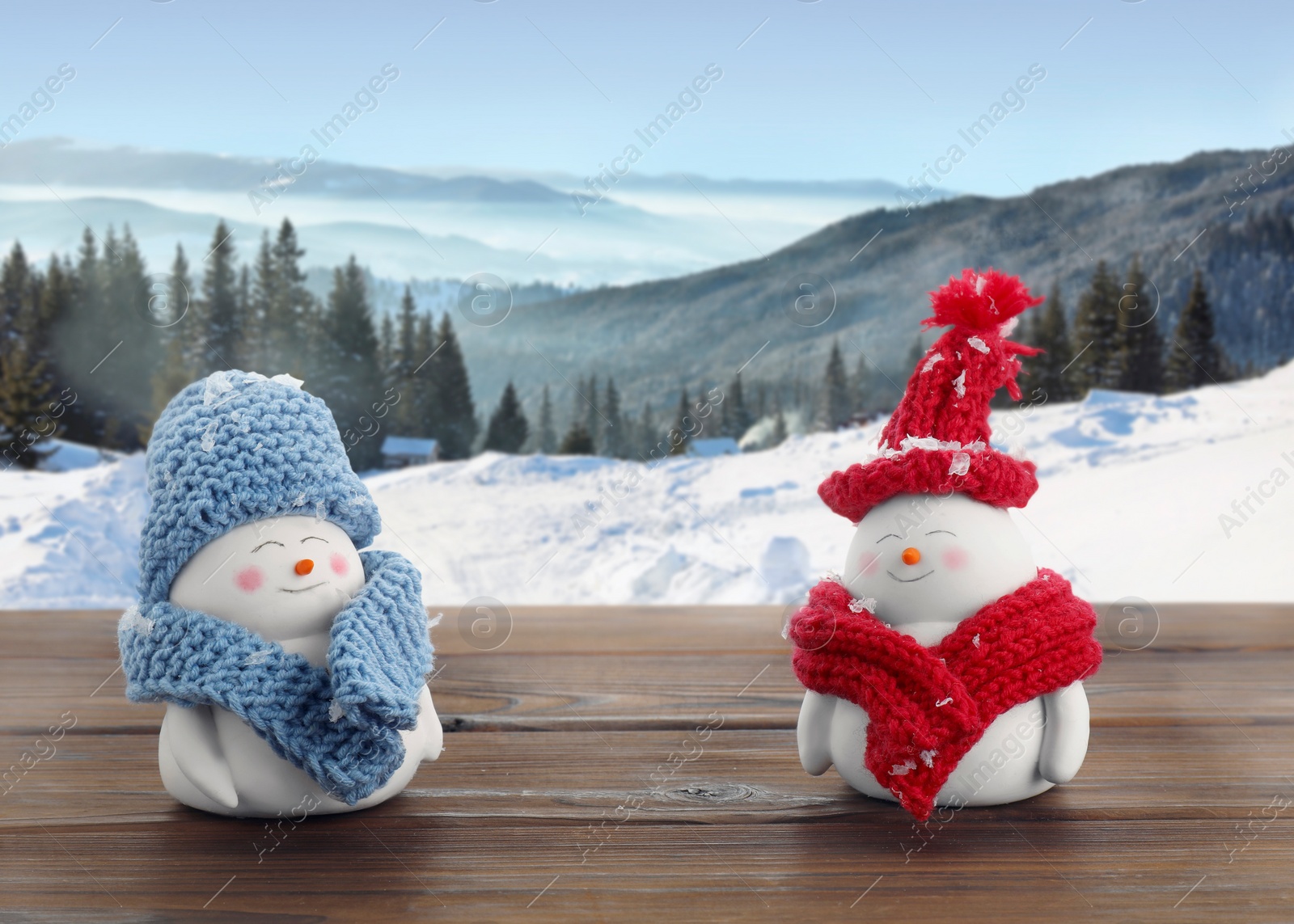 Image of Cute decorative snowmen on wooden table in mountains