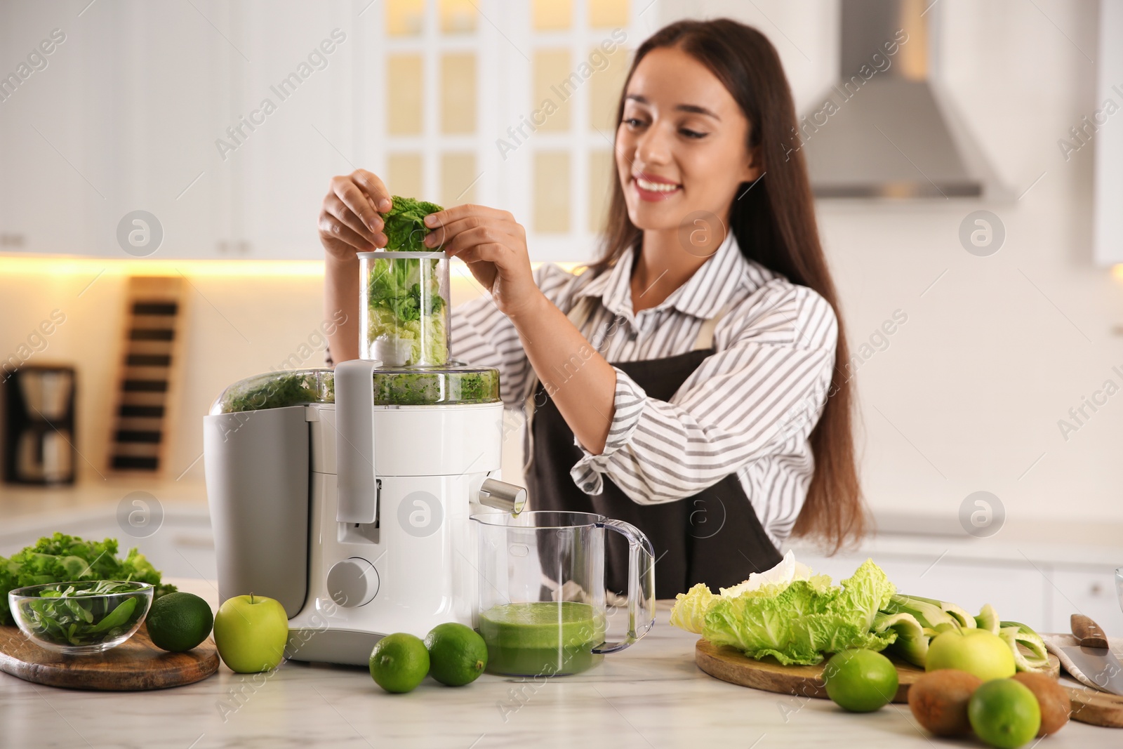 Photo of Young woman making tasty fresh juice at table in kitchen