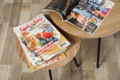Photo of Wooden nesting tables with different magazines indoors, above view