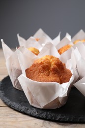 Photo of Delicious sweet muffins on wooden table against grey background, closeup