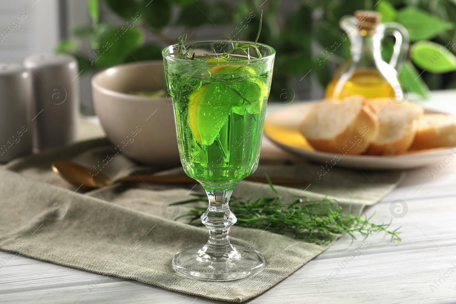 Photo of Delicious drink with tarragon in glass on white wooden table