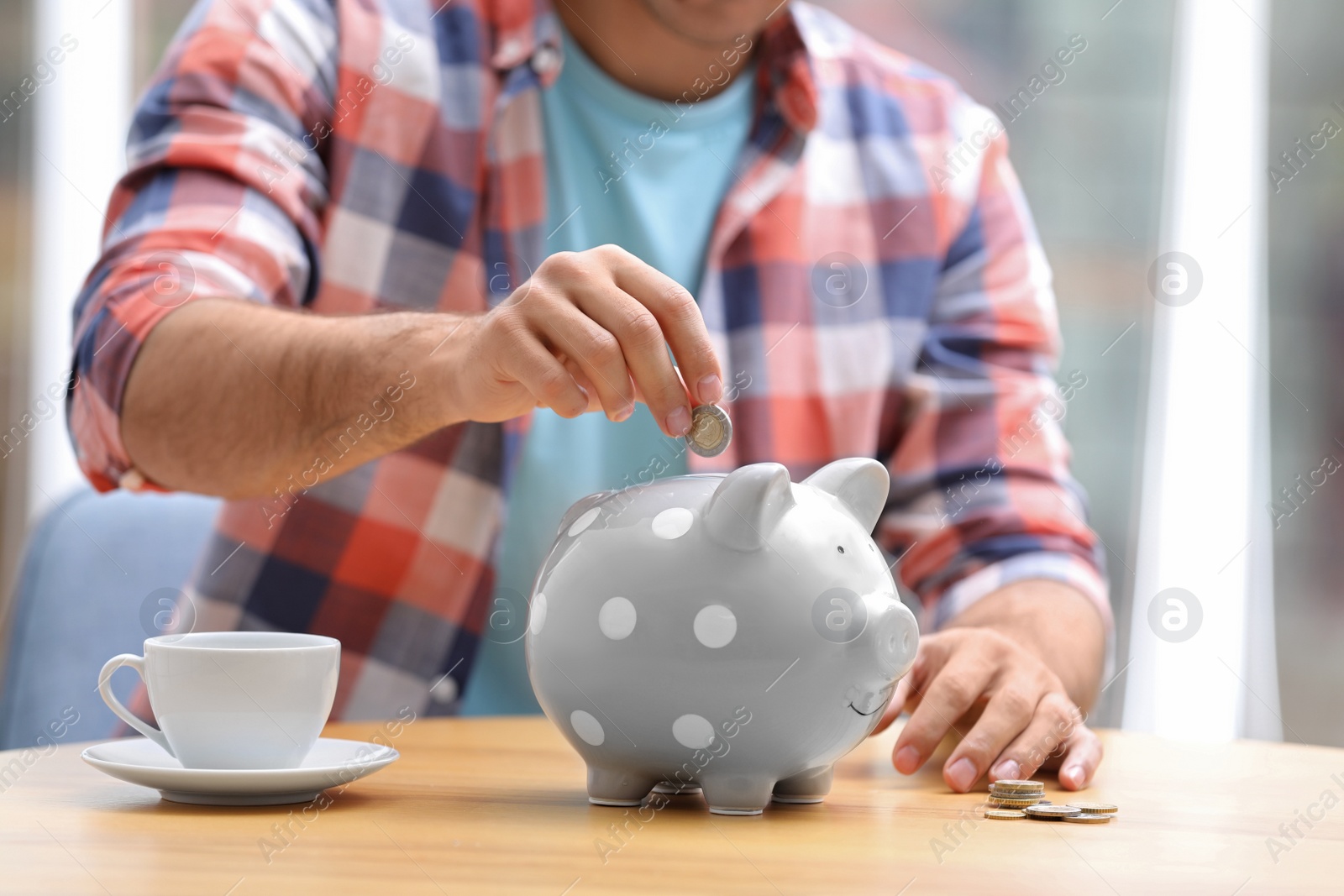 Photo of Man putting money into piggy bank at table, closeup