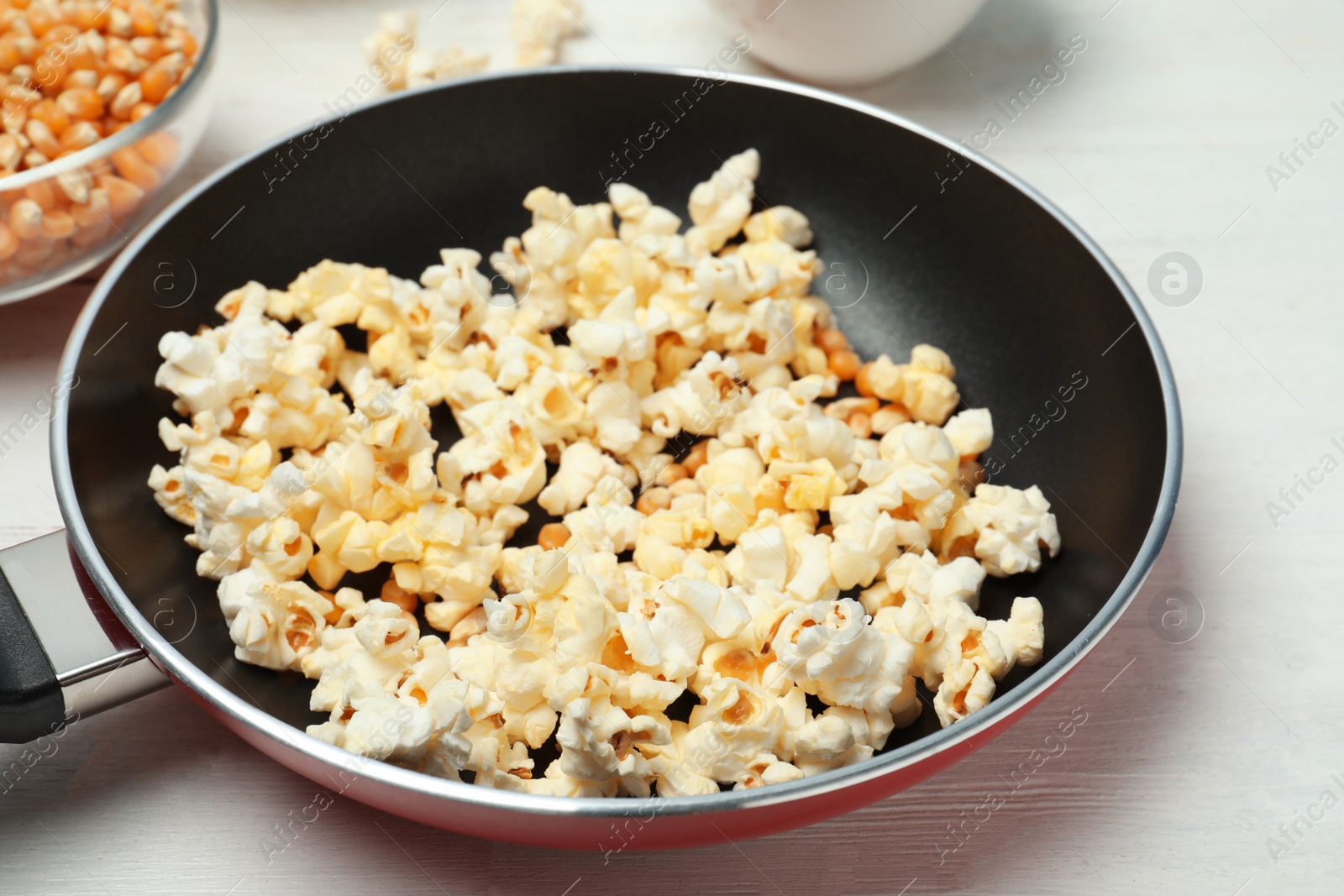 Photo of Frying pan with tasty popcorn on table