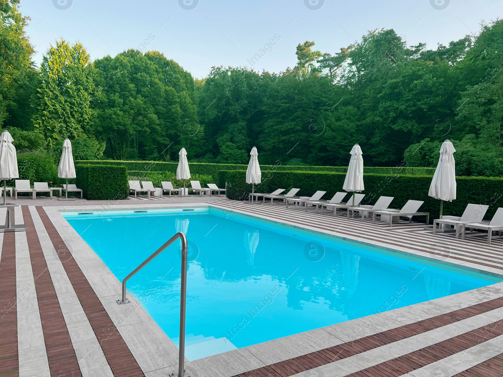 Photo of Outdoor swimming pool in luxury hotel on sunny summer day. Time for relax