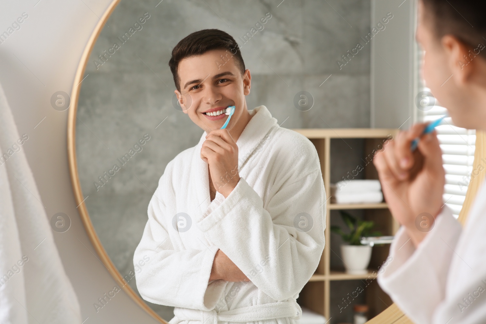 Photo of Man brushing his teeth with toothbrush near mirror in bathroom