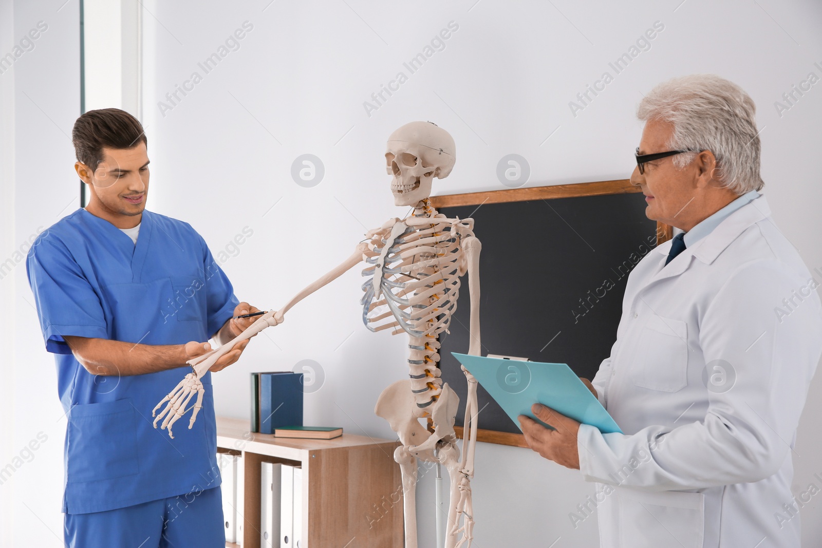 Photo of Medical student and professor studying human skeleton anatomy in classroom