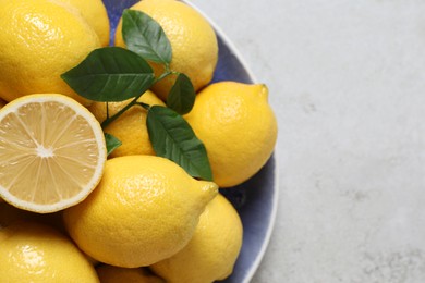Photo of Fresh lemons and green leaves on table, top view. Space for text