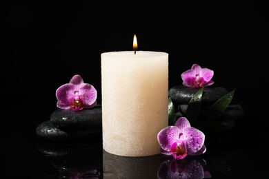 Photo of Composition with candle and spa stones on black background