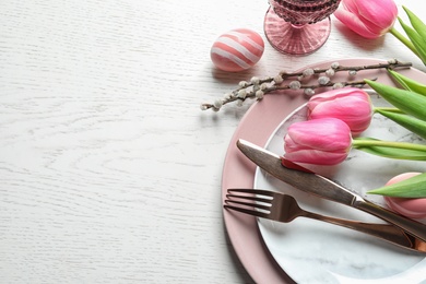 Photo of Festive Easter table setting with flowers on wooden background, above view. Space for text
