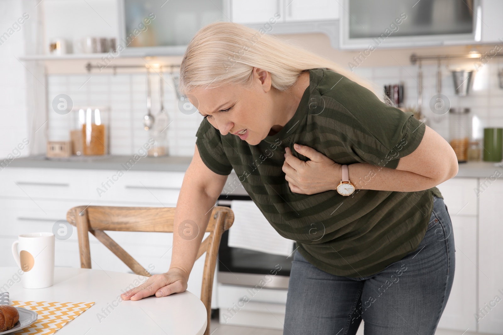 Photo of Mature woman having heart attack in kitchen