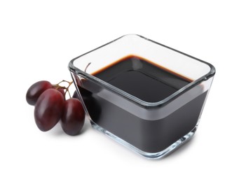 Photo of Balsamic vinegar in bowl and grapes isolated on white