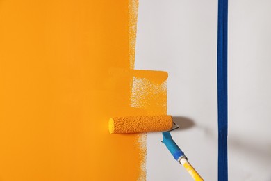 Photo of Painting wall with roller and orange dye