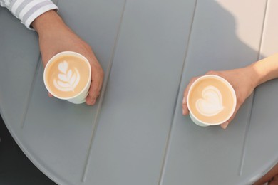 Coffee to go. Couple with paper cups at grey table, above view