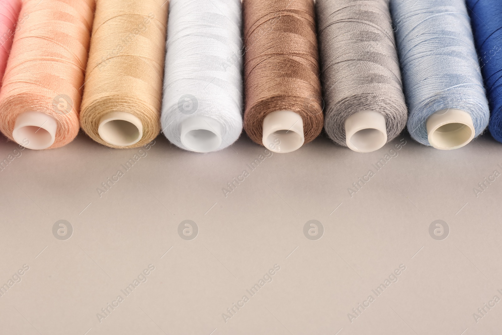 Photo of Different sewing threads on light grey background. Space for text